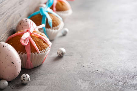 Happy Easter concept. Easter eggs and Easter cupcakes on a gray background, place for text.