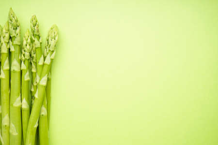 Fresh green asparagus on light green background, space for text. Flat lay.の写真素材