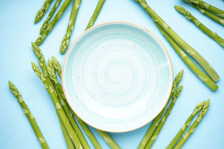 Green asparagus and a plate on a blue background, top view. Space for textの写真素材