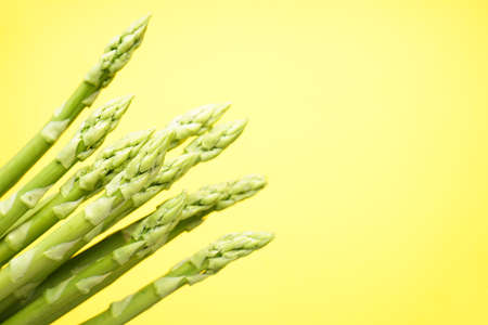 Green fresh asparagus on yellow background, place for text. Close-upの写真素材