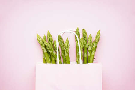 Green asparagus in a paper bag on a pink background. Flat lay.の写真素材