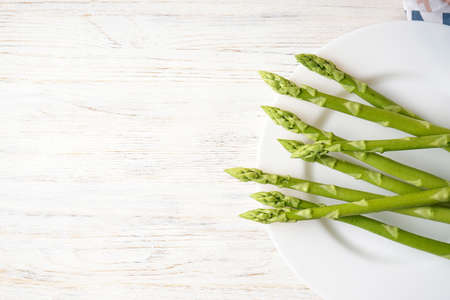 Fresh green asparagus in a plate on a wooden background, space for text.Top view.の写真素材