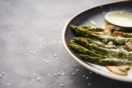 Baked asparagus and mushrooms with sauce in a plate on a gray background, place for text, close-up.の写真素材
