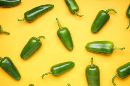 Green chili pepper. Group of jalapeno peppers on a yellow background, top view. Close-up.の写真素材