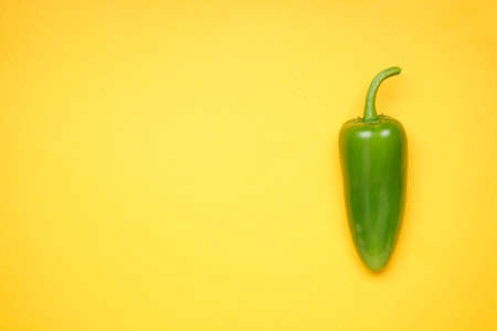 Green chili pepper. Jalapeno pepper on yellow background, place for text. Top view.の写真素材