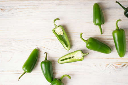Green jalapeno peppers wooden background, top view.