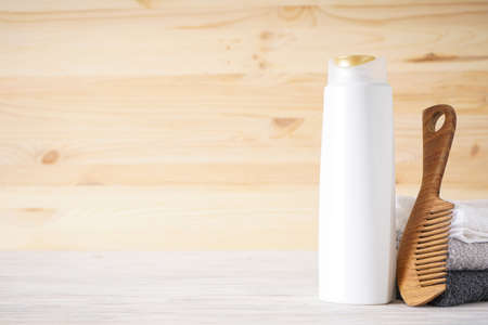 Towel, hair brush and shampoo on a wooden background, space for text.の写真素材
