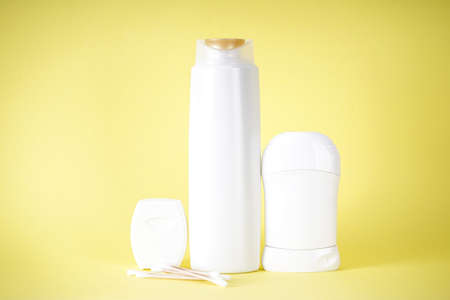 Shampoo bottle, deodorant and dental floss on yellow background.の写真素材