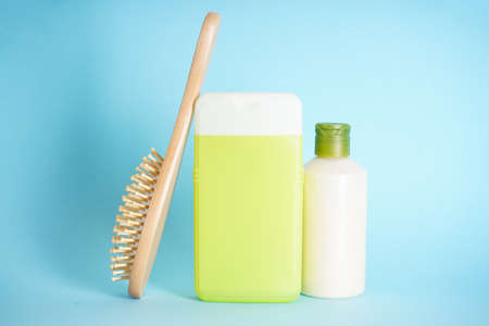 Plastic bottles for body care and a wooden hairbrush on blue background.の写真素材