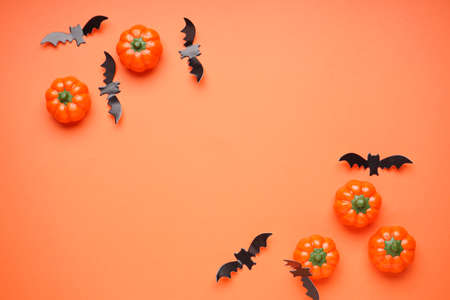Halloween concept. Halloween pumpkins and bats on a orange background, space for text, flat lay.