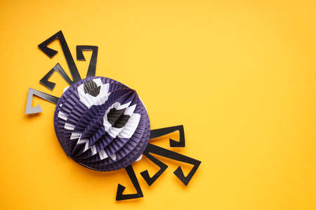Halloween decorations, paper spider on a yellow background, flat lay. Halloween concept, space for...