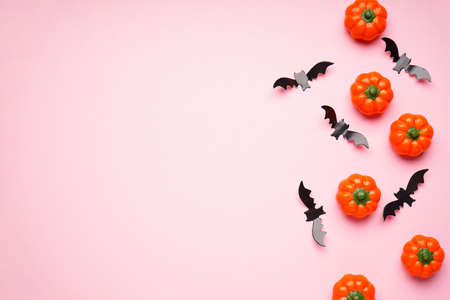 Halloween pumpkins and bats on a pink background, space for text, flat lay.
