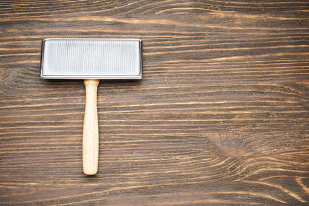 Brush for grooming wool. Brush for dogs on a wooden background. Flat lay.の写真素材