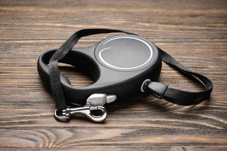 Black retractable leash for dogs on a wood background. Close-up.の写真素材