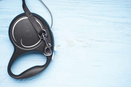Black retractable leash for dogs on a blue wooden background, close-up, space for text.の写真素材