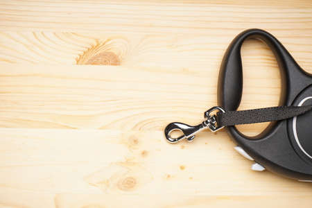 Black retractable leash for dogs on a wooden background, space for text, flat lay.の写真素材