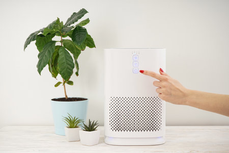 Woman turning on modern air purifier in the room. Protect PM 2.5の写真素材