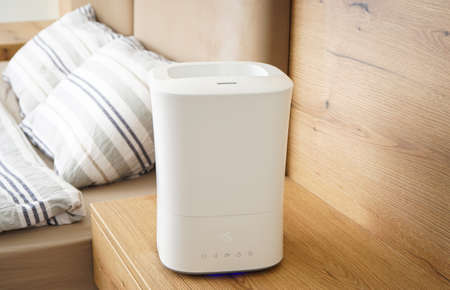 Aroma oil diffuser on the bedside table, steam from the air humidifier. Ultrasonic technology, increase in air humidity indoors.の写真素材