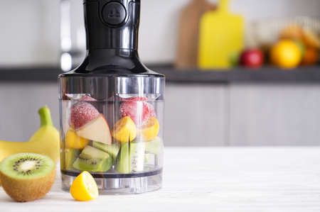 Hand blender for mixing organic raw fresh fruits for making vitamin diet smoothie, healthy food. Place for text.の写真素材