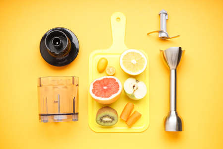 Electrical hand blender and accessories with sliced fruit on a yellow background. Flat lay.の写真素材