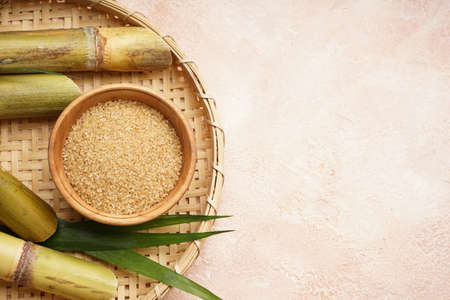 Brown sugar and sugar cane in a wooden tray on a beige background, space for text. top view.の写真素材