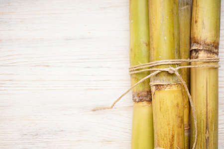 Tied sugarcane on white wooden background, space for text, close-up. top view.の写真素材