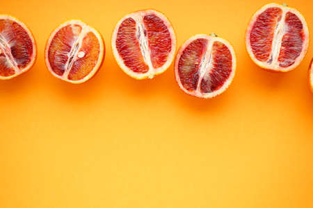 Halves of blood oranges on a orange background, space for text. top view.の写真素材