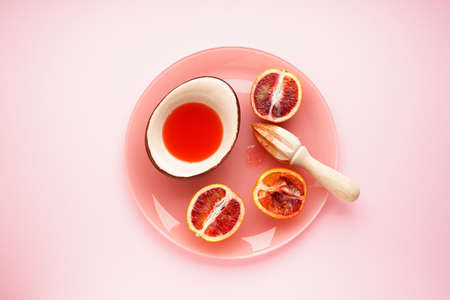 Blood oranges and a wooden juicer with blood orange juice on a pink background. top view.の写真素材