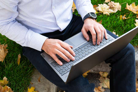 Young man using laptop in the park, top view.の写真素材