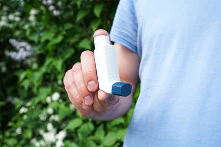 Male hand holding asthma inhaler on attack outdoor, closeup. Health and medical concept.の写真素材