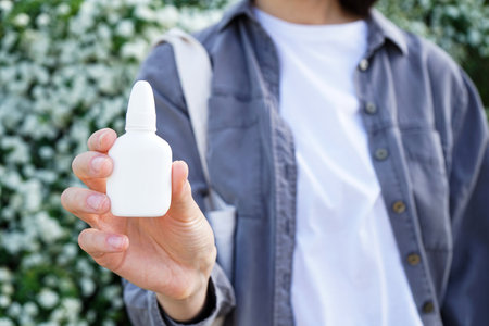 Hand of a young woman holdin nasal drops outdoors. close-up. Health and medical concept.の写真素材