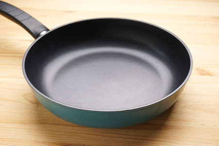 New frying pan on a wooden background, close-up.の写真素材