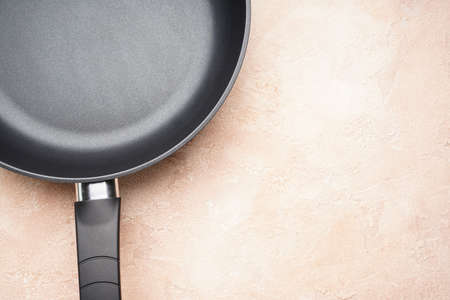 New frying pan and kitchen towel on a beige background, space for text. Top view, flat lay.の写真素材