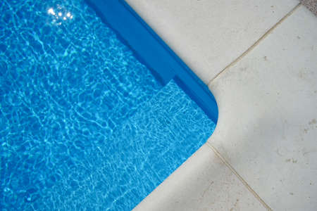 Swimming pool with blue water outdoors with stone gray edge, close-up. top view.の写真素材