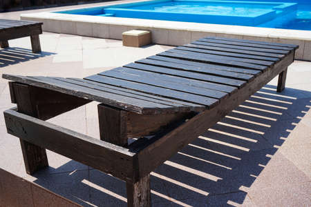 Wooden sun lounger near the outdoor pool, close-up.の写真素材