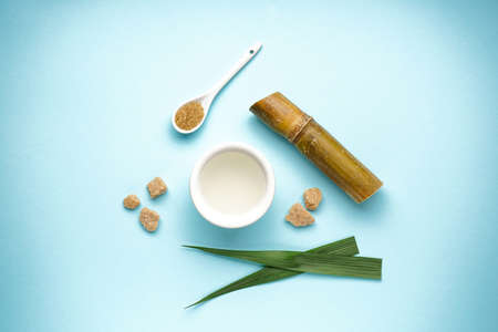 Sugar cane juice and brown sugar on blue background, top view.の写真素材
