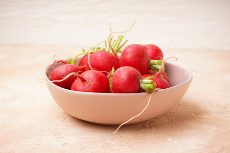 Ripe red radish in a bowl on a beige background, closeup. Fresh red radish.の写真素材