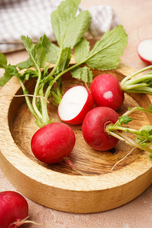 Ripe red radish in a wooden bowl on a beige background, fresh red radish. top view.の写真素材