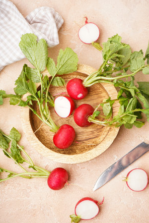 Ripe red radish in a wooden bowl on a beige background, fresh red radish. top view.の写真素材