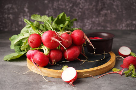 Fresh red radish with leaves on cutting board on a gray background.の写真素材