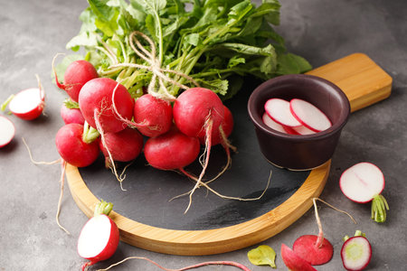 Fresh red radish with leaves on cutting board on gray background. close-up.の写真素材