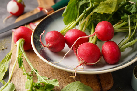 Ripe red radish in a bowl on a gray background, close-up. Fresh red radish.の写真素材