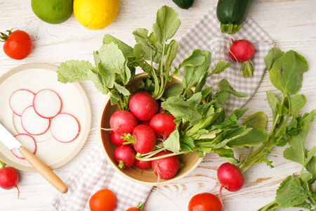 Bowl with radish and other spring vegetables on a wooden background, top view.の写真素材