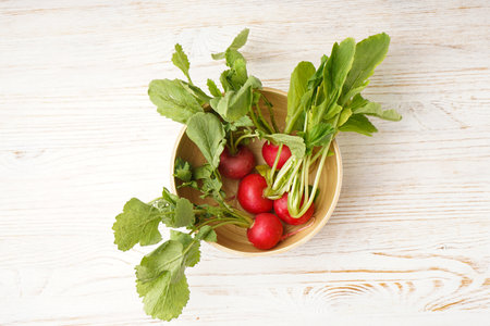 Ripe red radish in a bowl on a wooden background. top view. Fresh red radish.