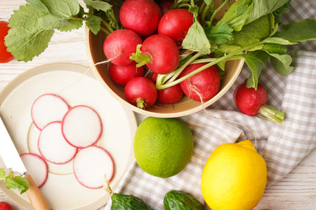 Bowl with radish and other spring vegetables on a wooden background, top view.の写真素材