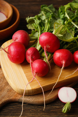 Fresh red radish and kitchen board on wooden background.の写真素材
