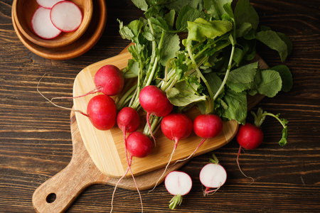 Fresh red radish and kitchen board on wooden background. flat lay.の写真素材