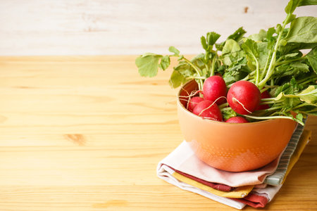 Fresh red radish in bowl on a wooden background with space for text.の写真素材