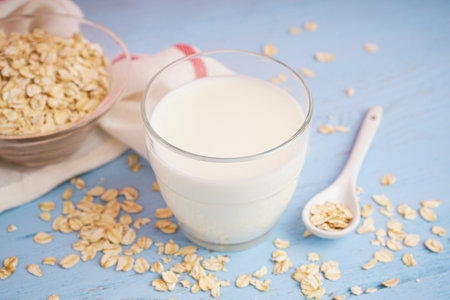 Glass of fresh milk on light blue wooden table background, with oatmeal.の写真素材