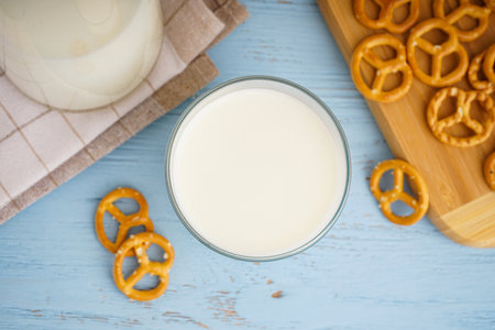 Glass and jug of fresh milk on wooden table against color background, with cookies. Flat lay.の写真素材